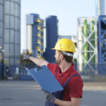 Laborer outside a factory working dressed with safety overalls e