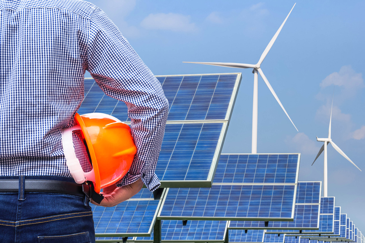 engineer stand holding yellow safety helmet front solar photovoltaic and wind turbines generating electricity power station alternative energy from the natural